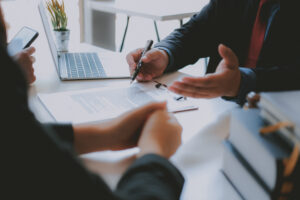 Closeup of people's hands on a desk with one person holding a pen. Estate Planning