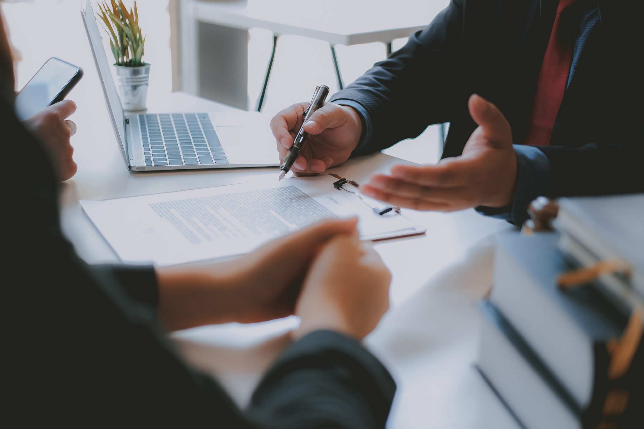 Closeup of people's hands on a desk with one person holding a pen. Estate Planning