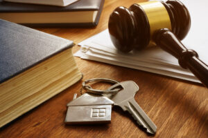 Close up of house key with gavel to the right and book to the left on desk. Real Estate law
